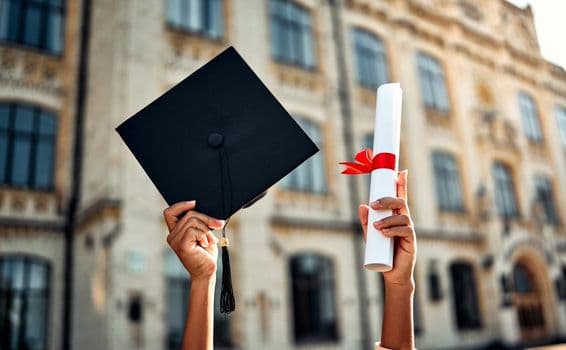 Graduation cap and diploma with red ribbon.