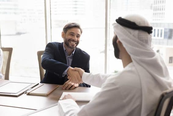 Cheerful businessman shaking hands with Arab partner.