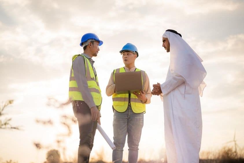 Asian engineer and Arab businessman discussing in construction.