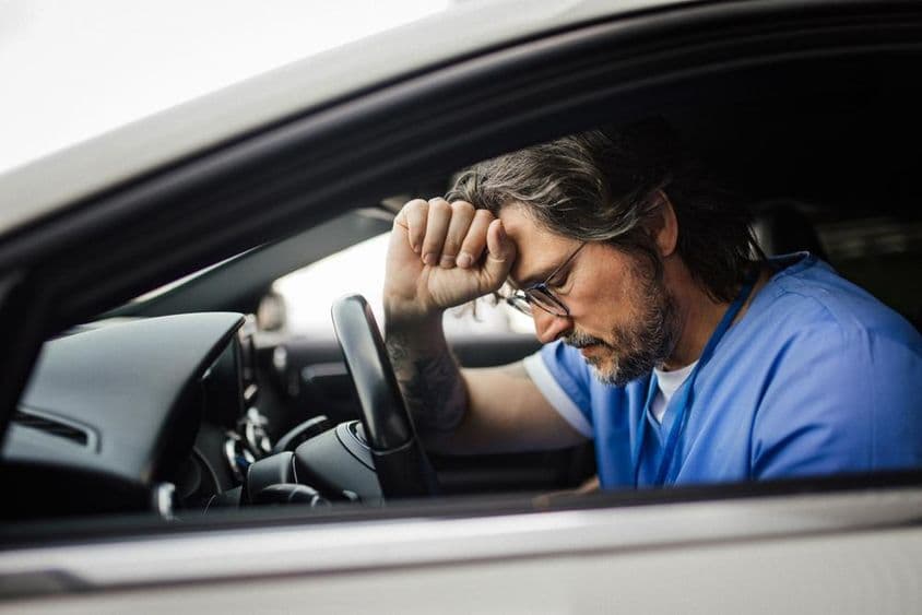 Doctor in car, exhausted.