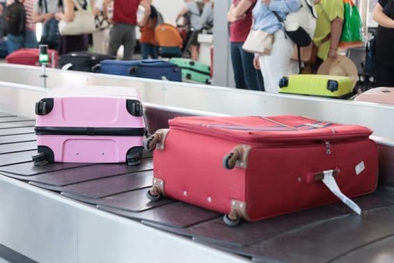 Suitcases on a luggage carousel at Dubai airport on a busy travel day.