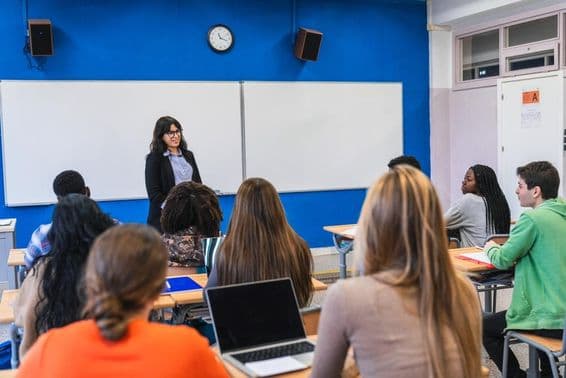 High school students listening to their teacher delivering a lesson in a modern classroom.