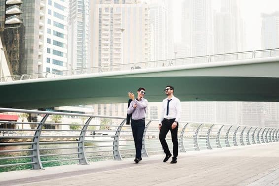 Two businessmen chatting while walking in Dubai Marina.