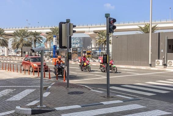 Three motorcycles and a car stop at a crosswalk on Sheikh Zayed Road.