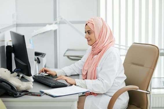 A young Middle-Eastern woman wearing a hijab working as a nurse at a medical clinic.