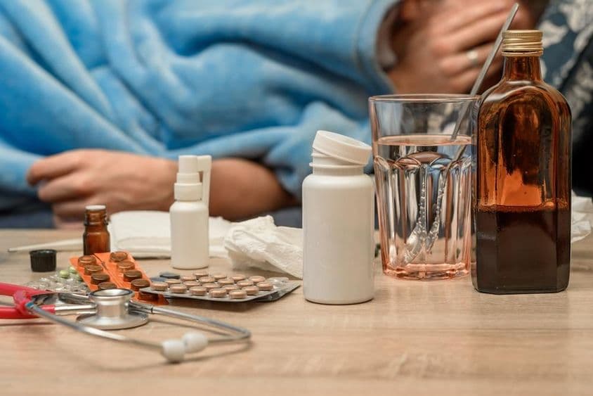 A man with a cold and fever lying in bed.