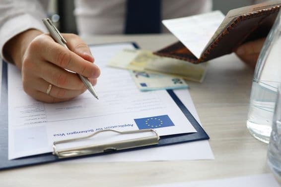 A man holding a passport and entering personal information on a Schengen visa application.