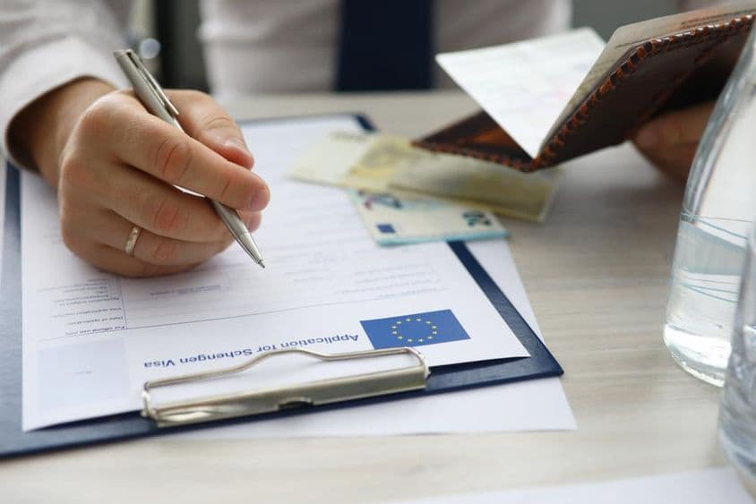 A man holding a passport and entering personal information on a Schengen visa application.