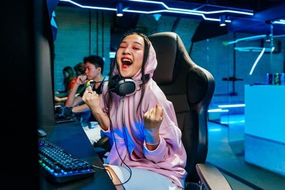 Beautiful young Asian woman playing video games in an internet cafe.