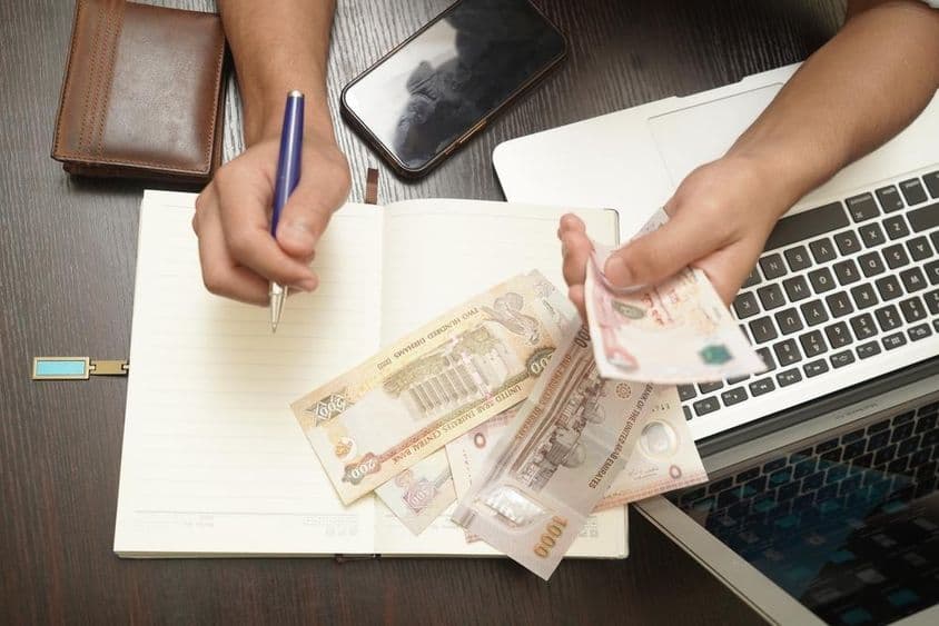 A man's hand carefully selects banknotes, featuring various denominations.