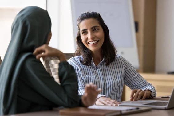 Spanish-speaking businesswoman conversing with Arab female colleague.