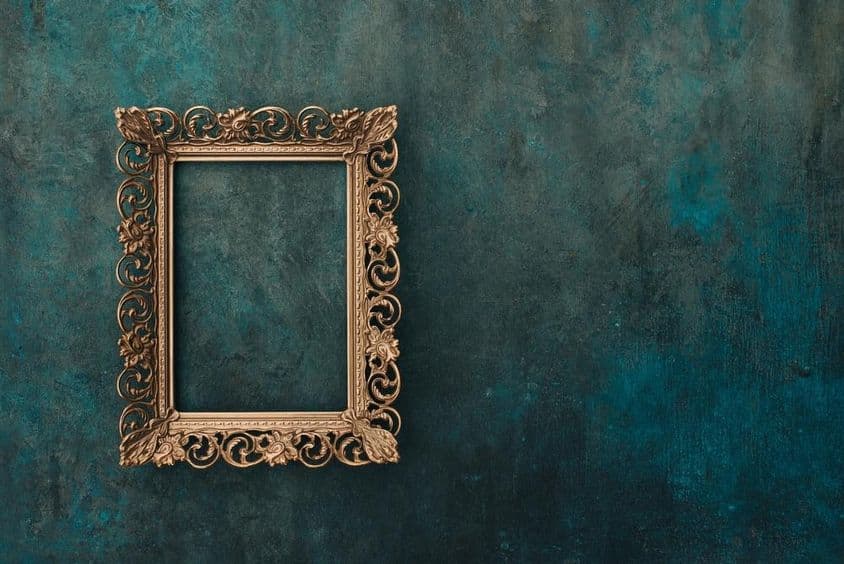 Vintage openwork bronze metal frame on a blue and green aged wall.
