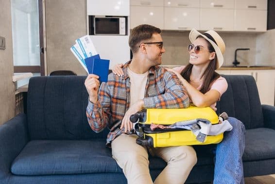 Smiling couple with passports and boarding passes in hand, with a suitcase.