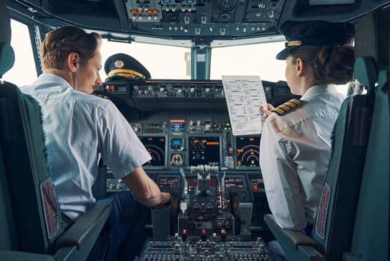 A male captain and female co-pilot sitting in the cockpit.