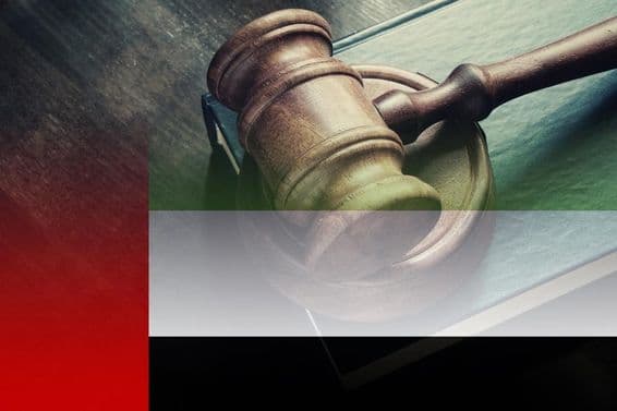 Judge's gavel with book on the table and UAE flag.