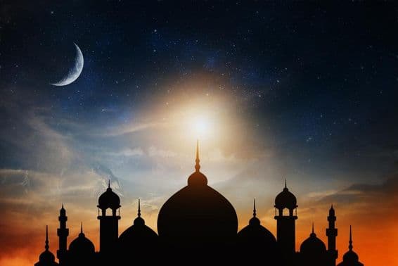 Mosque domes against a deep blue twilight sky with a crescent moon in the background.