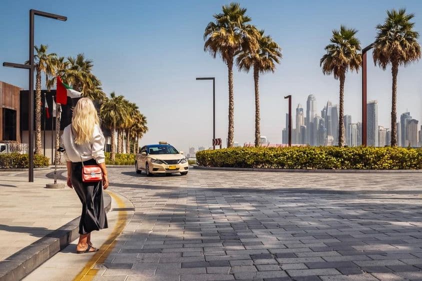 A woman in Dubai waiting for a taxi on the street.