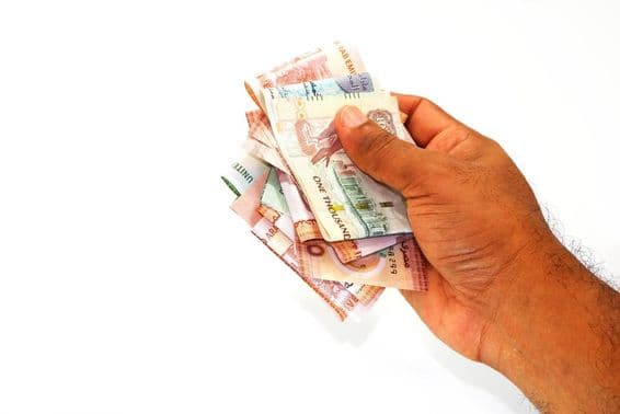 Dirham banknotes held in hand.
