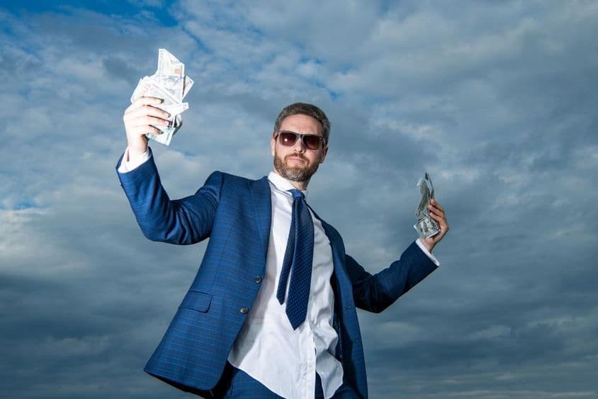 A billionaire man with money in a suit.