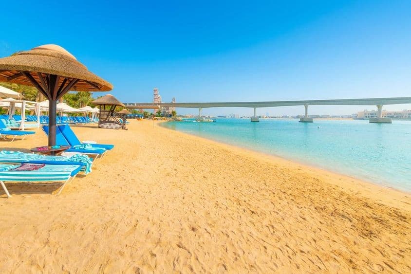 On a sandy beach of the Arabian Gulf, the Palm Jumeirah Island monorail crosses the sea in Dubai.