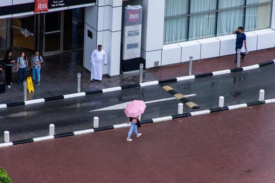 A girl with an umbrella walking in the rain in Dubai City.