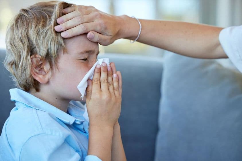 Feverish sick child at home on the couch.
