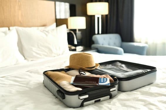 Packed suitcase with passport and tickets on a bed.