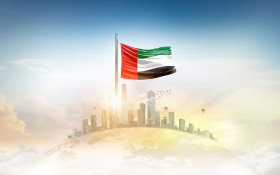 United Arab Emirates flag waving in front of skyscrapers.