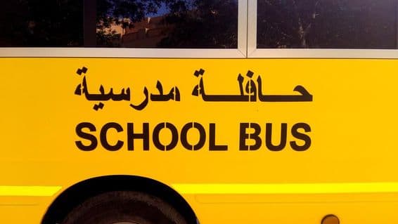 A bus side with school bus written in Arabic.