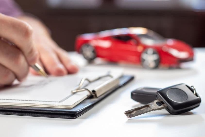 Man signing vehicle insurance document.