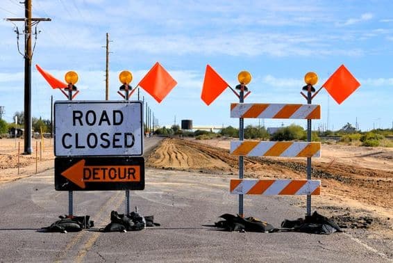 road closure detour signs and orange warning flags.