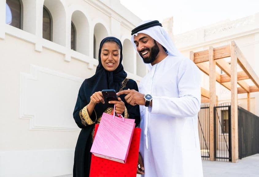 Traditional Arab couple in Emirati attire dating outdoors.