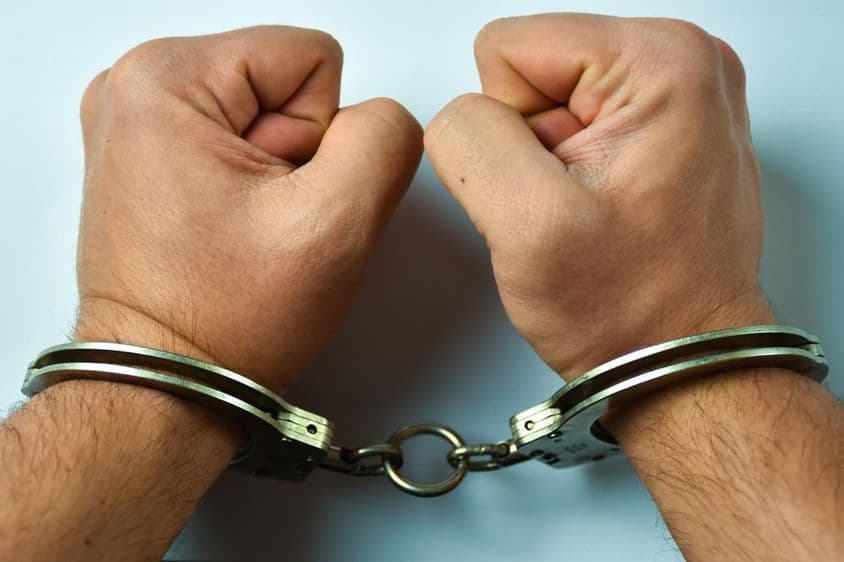 Handcuffed hands on a table.