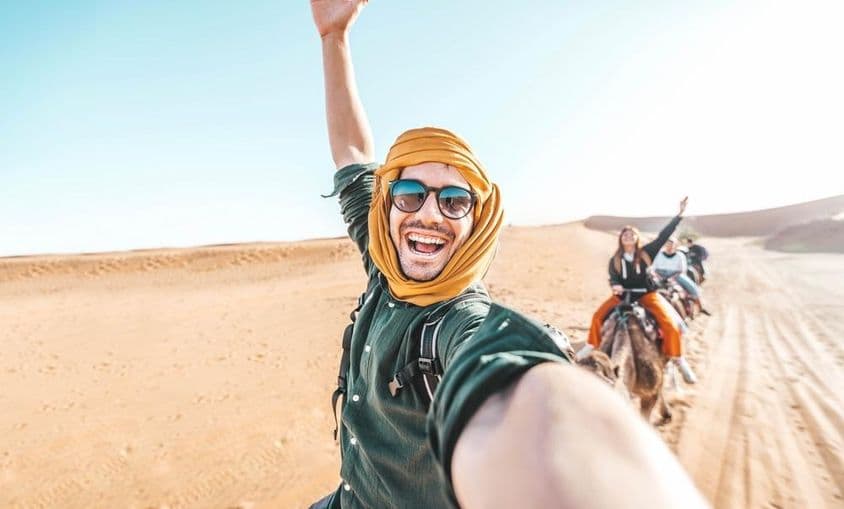 Happy tourist enjoying camel ride in the desert.