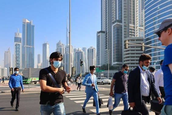 People walking at a crosswalk in Dubai's business center.