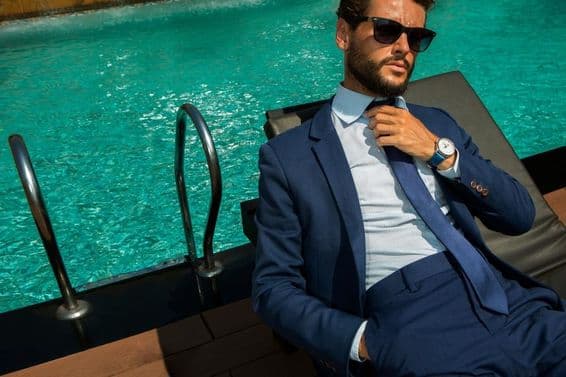 Successful businessman in a blue classic suit near luxury swimming pool.