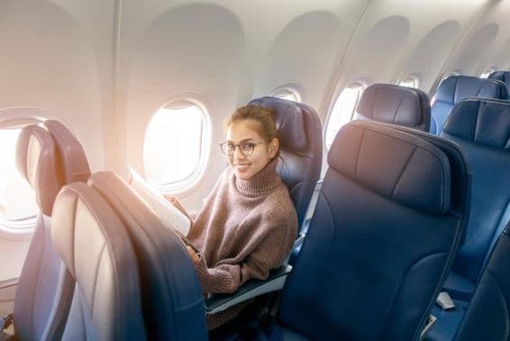 Asian woman reading a magazine on an airplane.