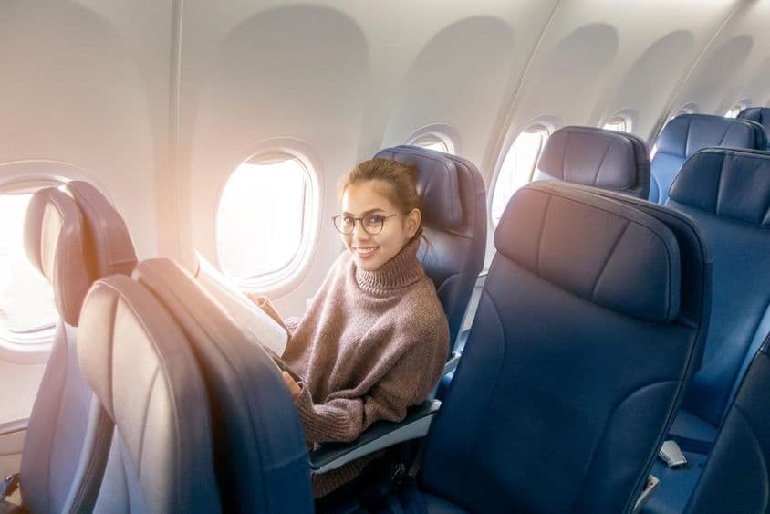 Asian woman reading a magazine on an airplane.