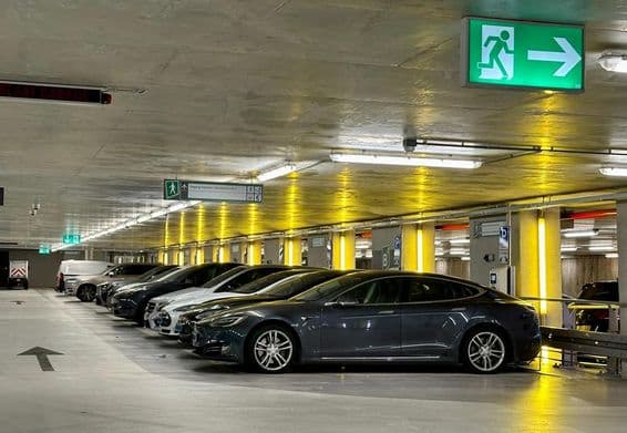 Yellow neon lights illuminate spaces reserved for electric vehicles.