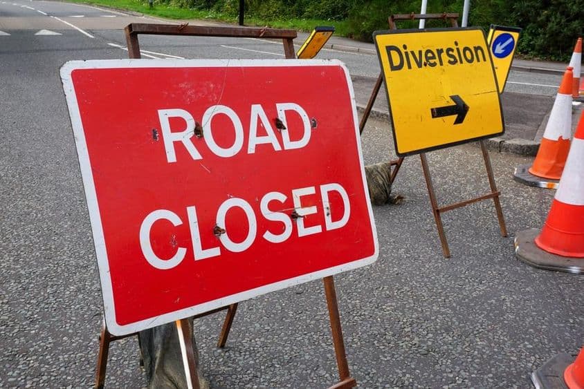 Road closure and diversion signs at a construction area.