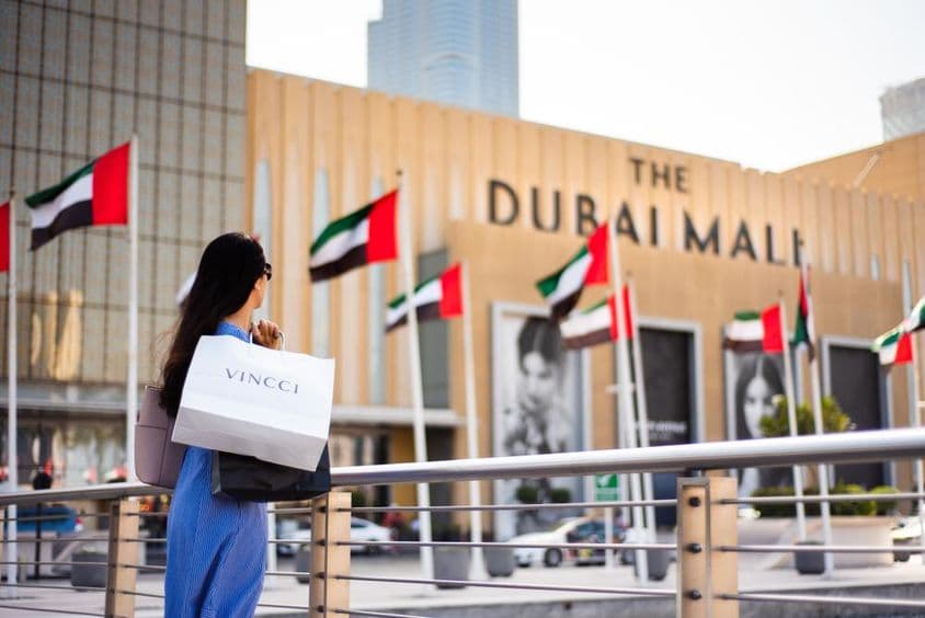 Asian tourist with shopping bags at the main entrance of Dubai Mall.