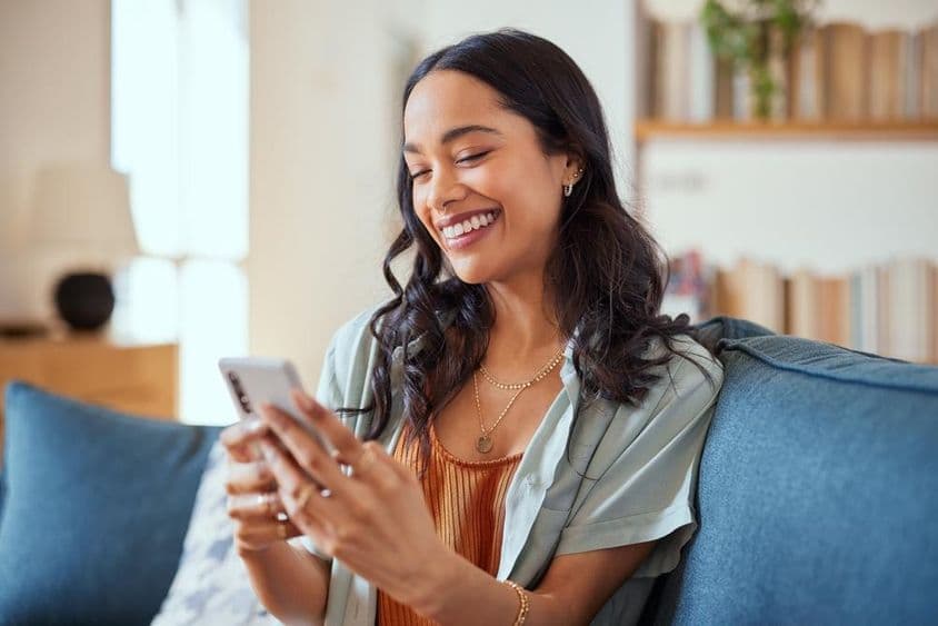 Joyful Latina woman using a smartphone.