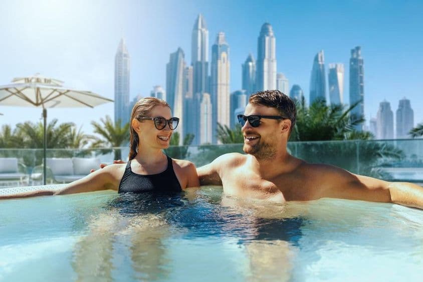 Happy young couple relax in an outdoor jacuzzi at a Dubai hotel.