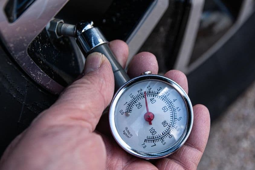 Check tire pressure with a pressure gauge for proper inflation in a car tire.