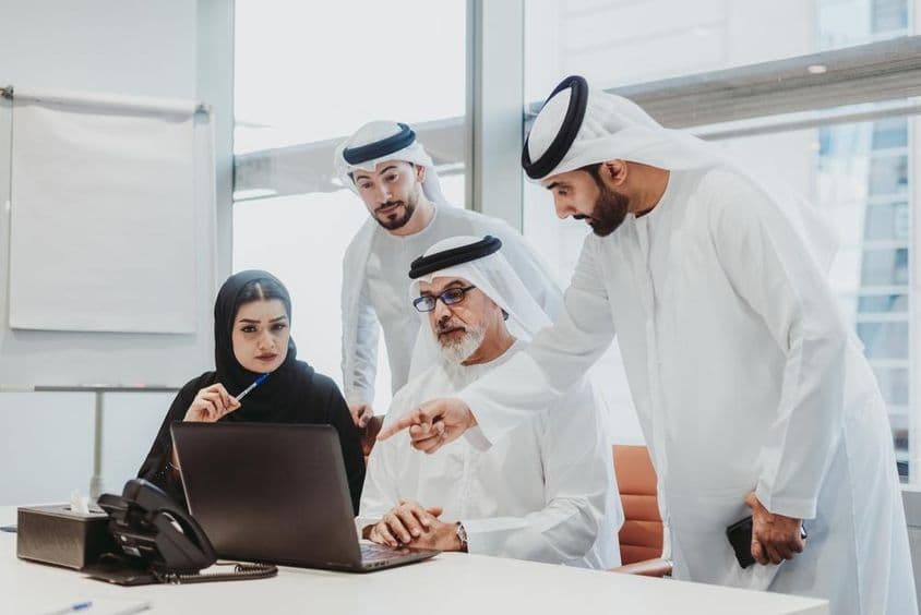 Businessmen wearing Emirati attire in a meeting in an office in Dubai.