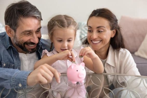 Happy parents teaching daughter to save money.