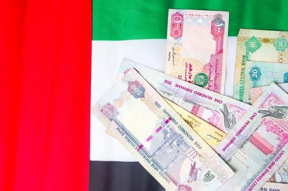UAE dirham banknotes atop the national flag.