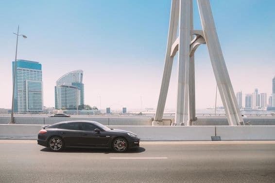 Black Porsche Panamera car moves on a Dubai city street.