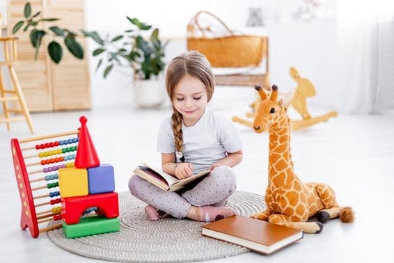 A little girl among toys in a bright children's room.
