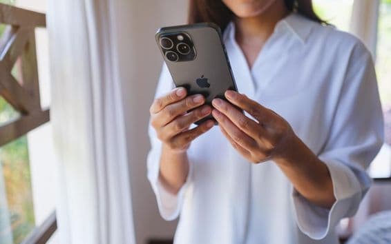 A woman using an iPhone 15 Pro Max at home.